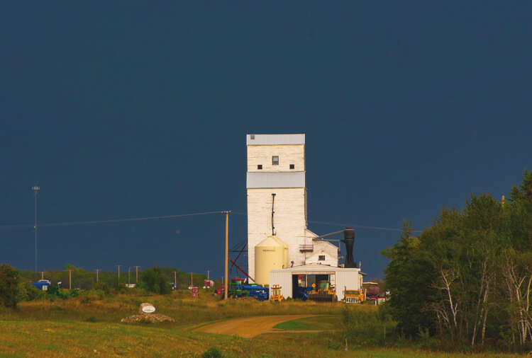 Dark clouds signalling bad weather form behind a grain elevator at Borden, SK.